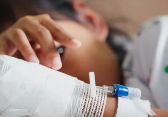 Sick kid feeling unwell lying down in an emergency room bed.