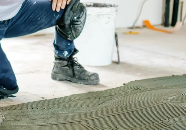 A front view of a construction worker's hands installing new flooring.