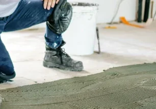 A front view of a construction worker's hands installing new flooring.