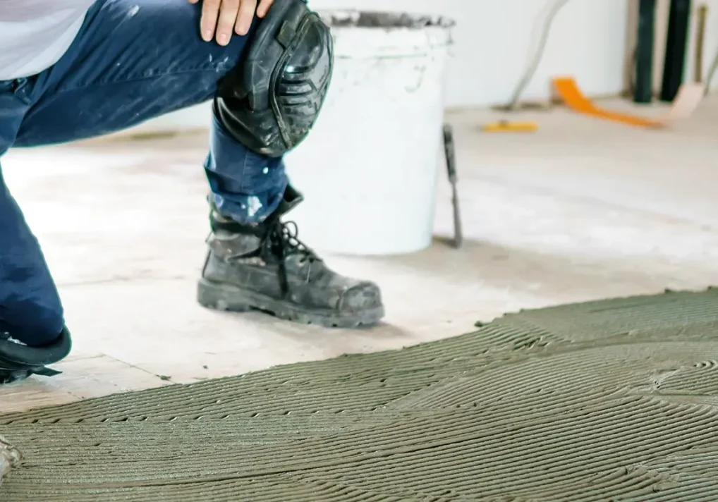 A front view of a construction worker's hands installing new flooring.