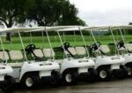 A photograph taken of golf carts parked in a row waiting for the rain to clear.