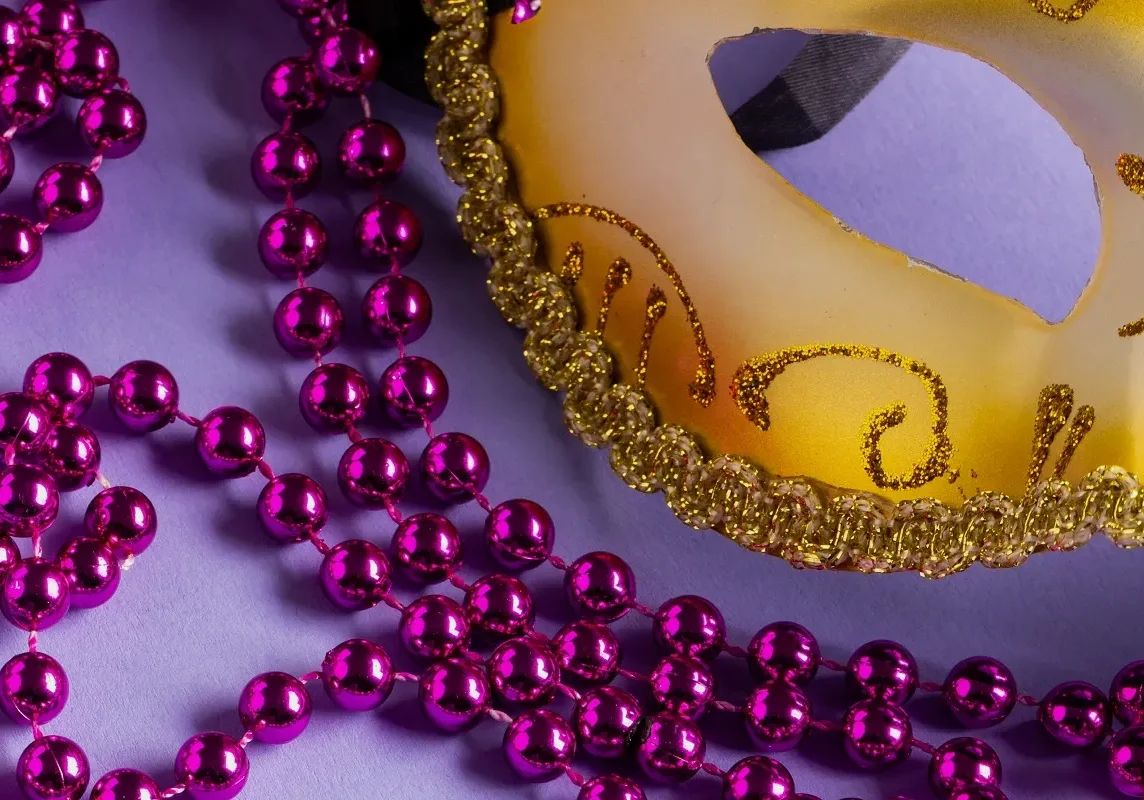 Colorful Mardi Gras beads and carnival mask on blue background