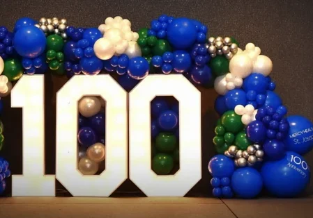 An indoor balloon wreath and light display that says 100.