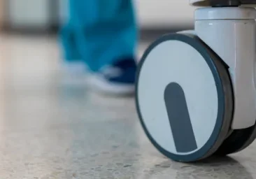 A nurse pushing a cart down a hospital hallway.